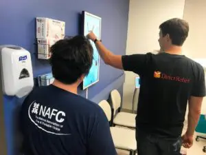 Direct-Relief two men looking at screen on wall