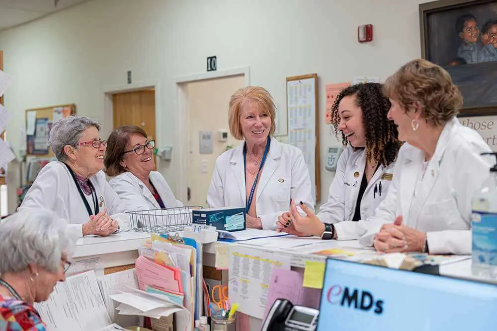 51683728325_ac0f230328_o 5 doctors smiling and chatting around receptionist desk