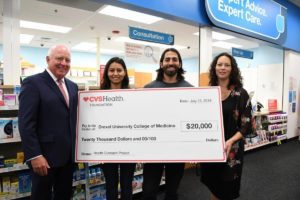 four people smiling holding cvs foundation check